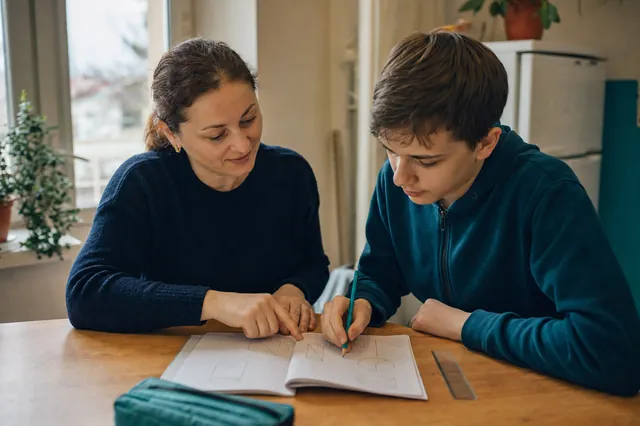 O profesoară și un elev rezolvă probleme de geometrie la masă